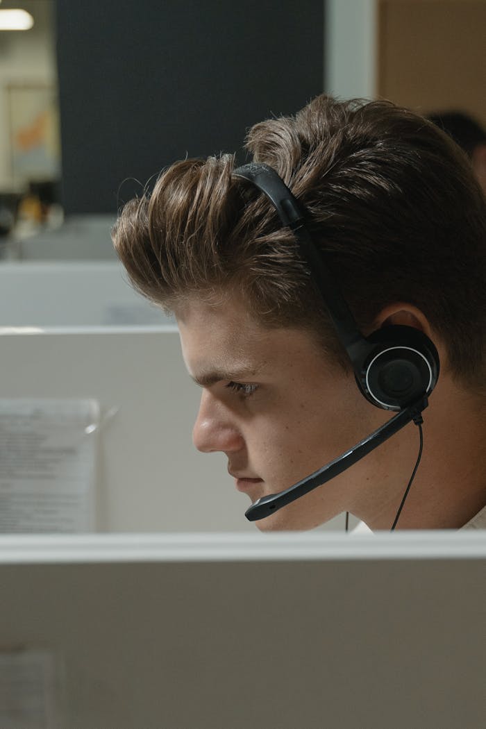 Close-up of a focused male call center agent wearing a black headset at work.